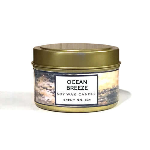 Ocean Breeze scented soy wax candle in gold metal tin, featuring fresh scents of breeze and cotton blossom.
